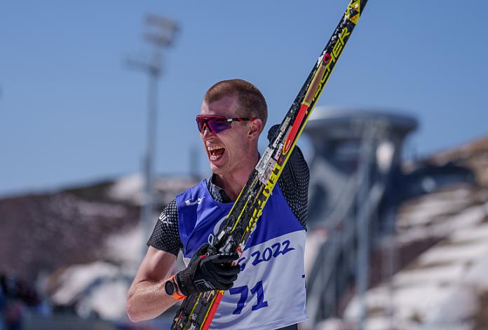 Mark Arendz celebrates winning gold at Beijing 2022 while holding his skis