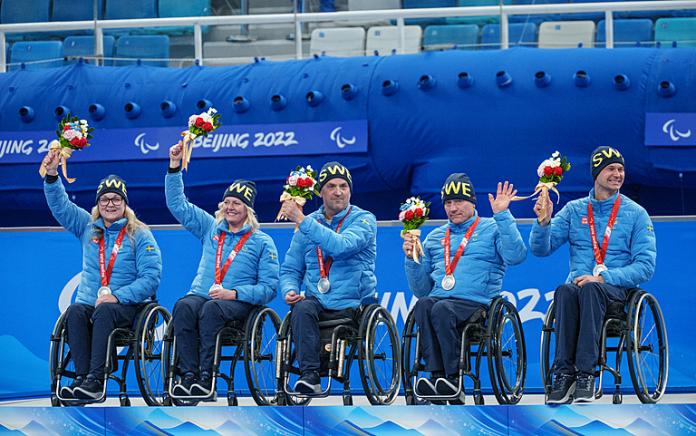 The Swedish wheelchair curling team smile and wave after receiving their silver medal