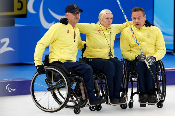 Three Swedish wheelchair curlers link arms