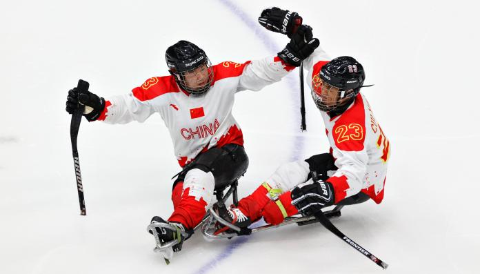 Two players celebrating with raised arms on their sleds.