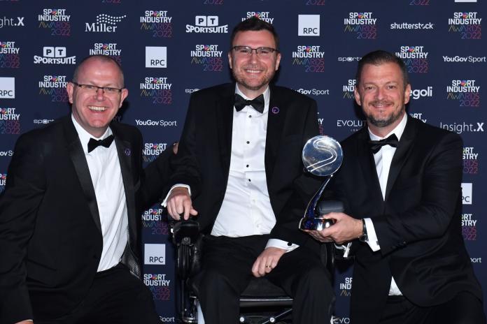 IPC President Andrew Parsons holds the award trophy next to IDA President Vladimir Cuk, centre, and IPC Chief Marketing and Communications Officer Craig Spence.
