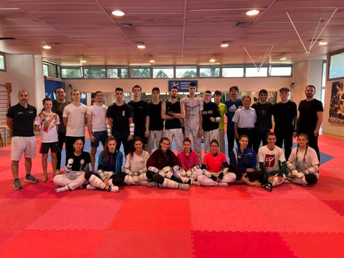 Italy's able-bodied and Para taekwondo athletes pose for a group photo on a mat.