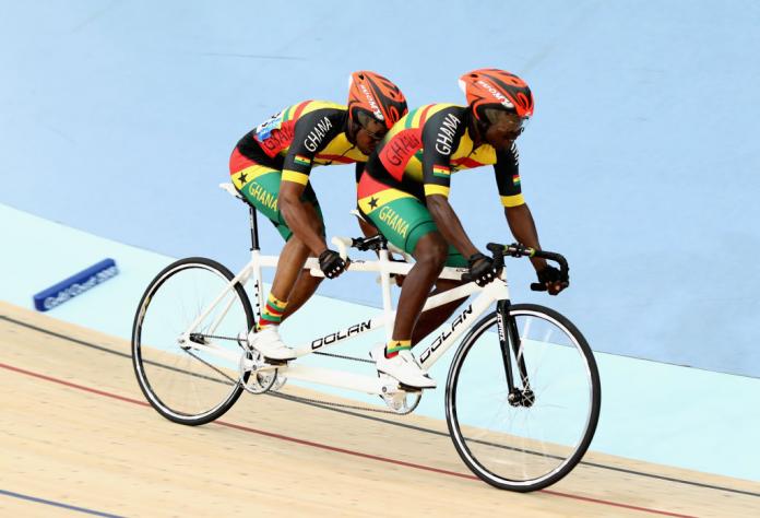 Frederick Assor and pilot Rudolf Mensahcompete race at the velodrome on a tandem bike in the Ghanian team kit.
