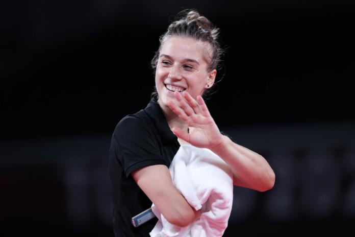 Natalia Partyka waves as she leaves the competition hall with her racquet and towel.