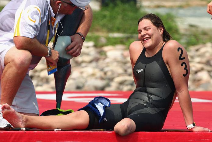 A marathon swimmer with a left leg amputation smiles as she takes a break on the shore.