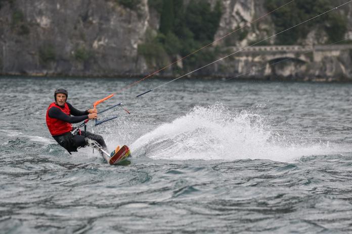 A male kiteboarder with a right leg prosthetic sails on the water.