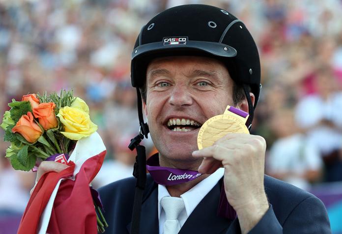 An equestrian rider holds up his gold medal at the London 2012 Paralympic Games.