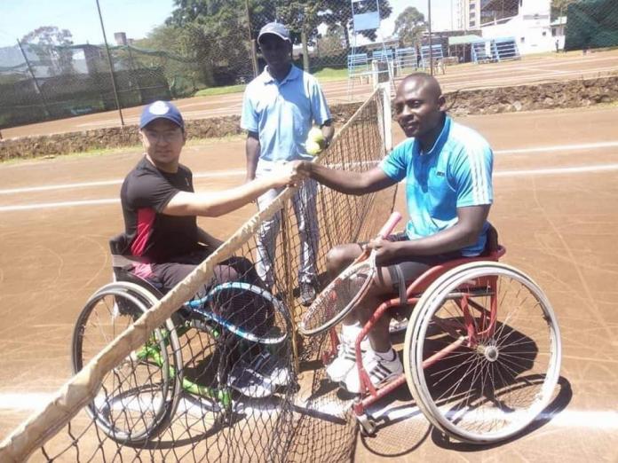 Two wheelchair tennis players shake hands over the net.