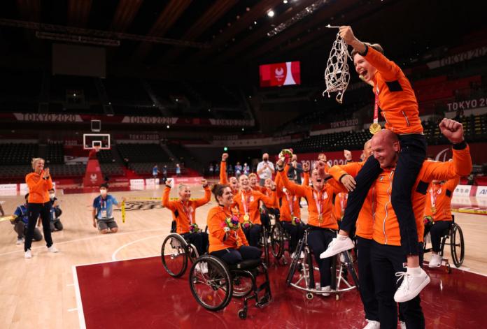 Bo Kramer cuts down the net as she sits on the shoulders of her coach with her teammates watching and celebrating with her.