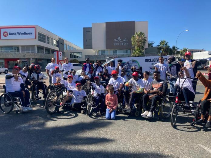 A group of hand cyclists pose for a photo together.