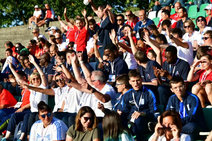 Members of the French delegation wave from the stands during the opening ceremony.