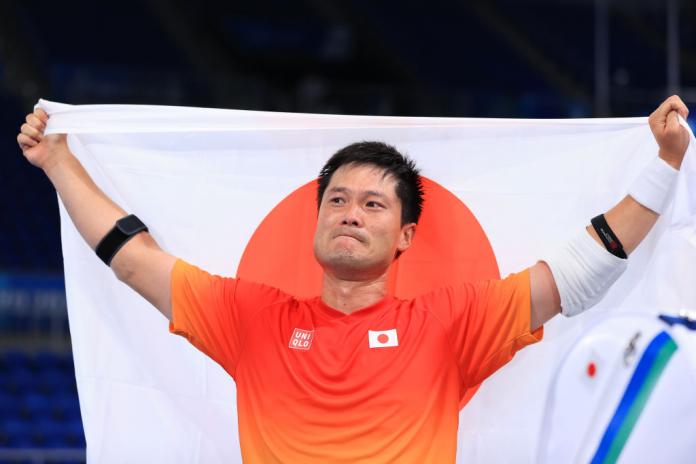 Wheelchair tennis player Shingo Kunieda holds the Japanese flag after winning the men's singles tournament at Tokyo 2020.