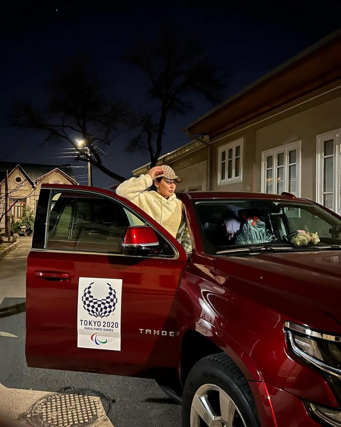 A female athlete poses from the front seat of a scarlet SUV.