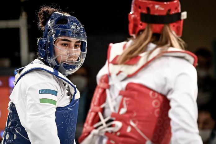 A fighter looks at her opponent in the midst of a taekwondo competition bout.