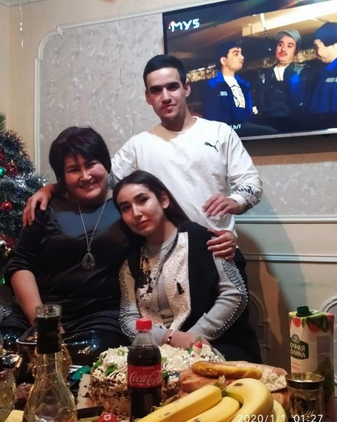 An athlete poses for a photo with her mother and brother in front of a table set with a New Year's banquet.