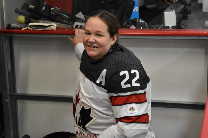 A female Para ice hockey player smiles at the venue of the Para Ice Hockey Women's World Challenge.