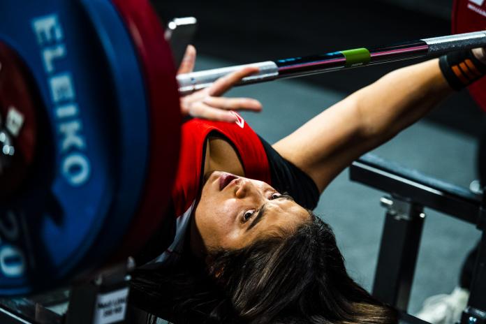 A female powerlifter looks up at the bar as she prepares to do a lift.