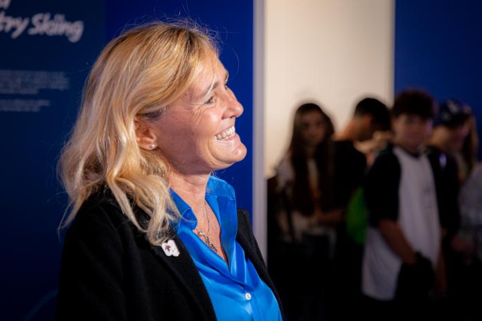 A woman in business attire smiles during an official event.