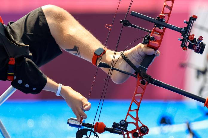 A closeup of feet that are holding an archery bow.