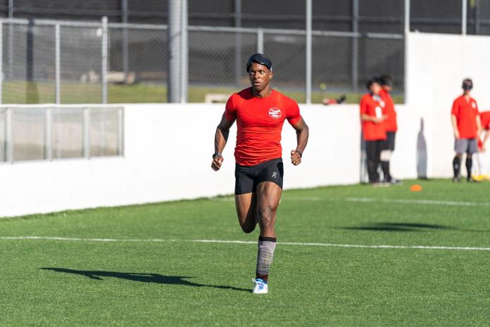 A male runner runs on a football pitch