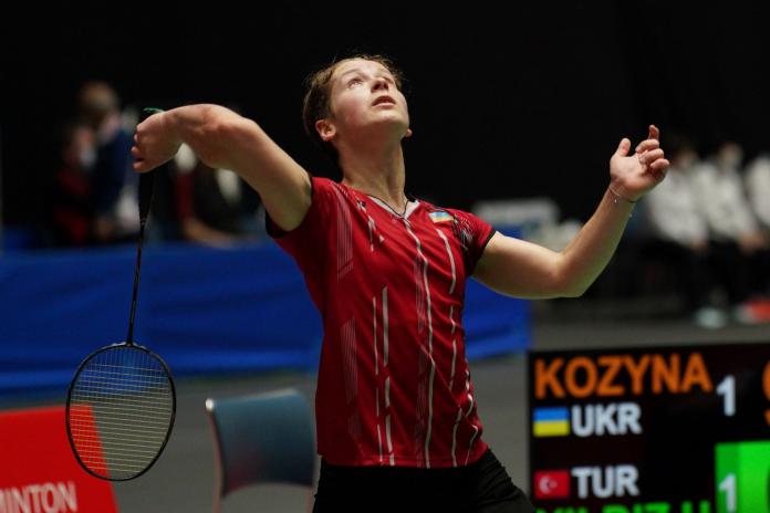 A female Para badminton player holds the racket with her right hand and looks up 