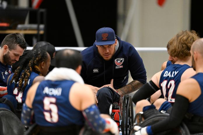 A man using a wheelchair speaks to wheelchair rugby players