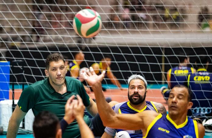 Three male athletes playing sitting volleyball