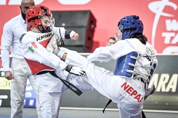 A female Para taekwondo athlete from Nepal kicks an athlete from Mexico in a competition bout.