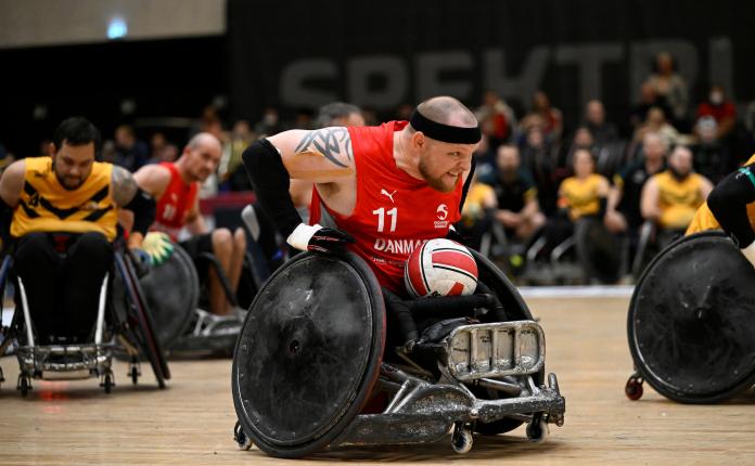 A male wheelchair rugby player carries the ball during a match