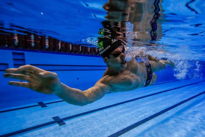An underwater shot of a male swimmer as he glides through the water, his right arm outstretched towards the camera.