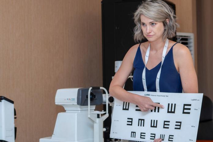 A female optometrist points to a chart used to determine eyesight.