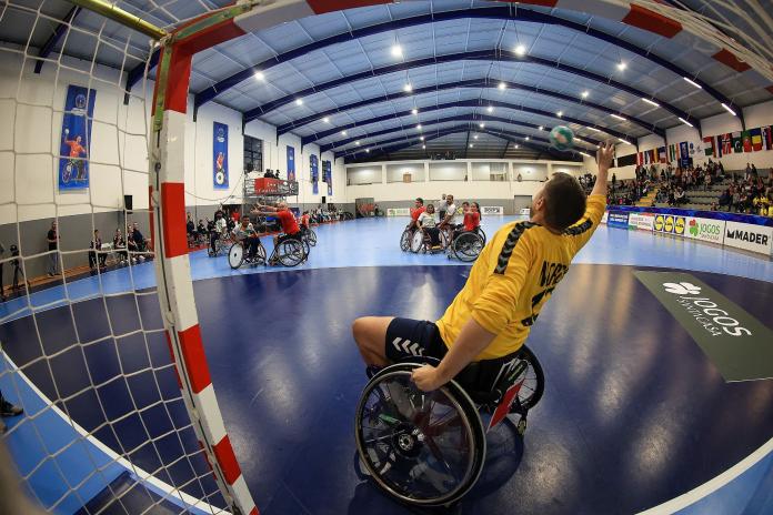 A view from the net as a Norwegian goalkeeper in a wheelchair stretches out his hand to catch the ball.