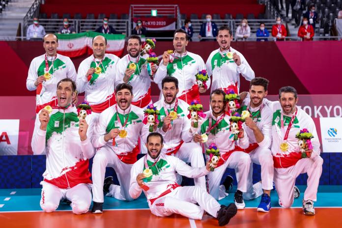 The players of the Iranian men's sitting volleyball team pose with their gold medals on the competition field.