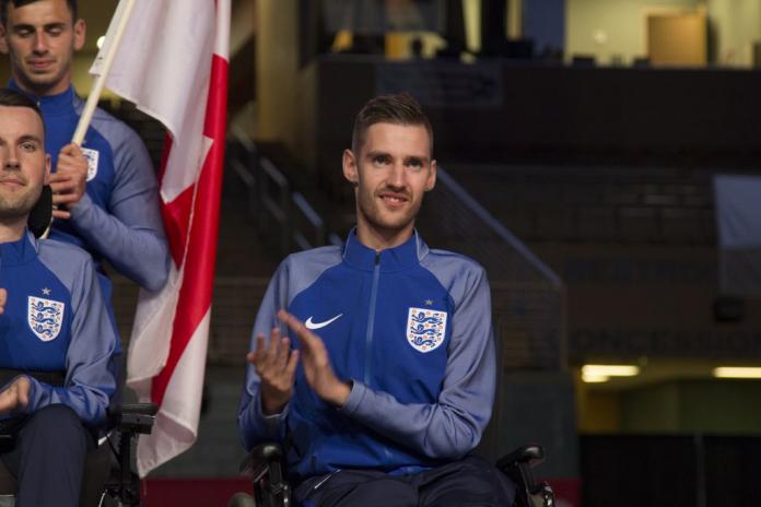 A male athlete on a wheelchair claps his hands