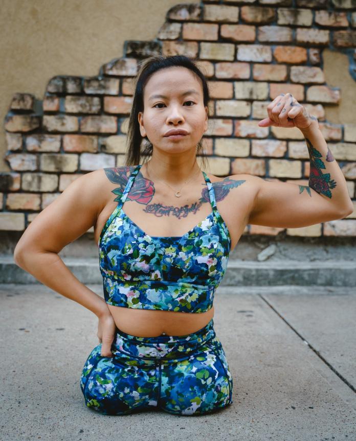 A female model without legs below the hip poses in exercise gear in a street fashion shoot.