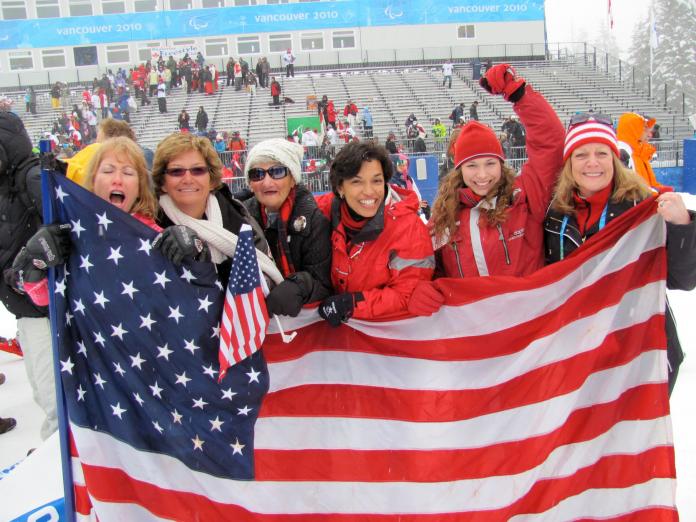 Six women hold a large American flag in front of the stands at the Vancouver 2010 Paralympic Games.