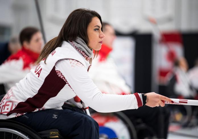 A female wheelchair curler photographed from her right side.