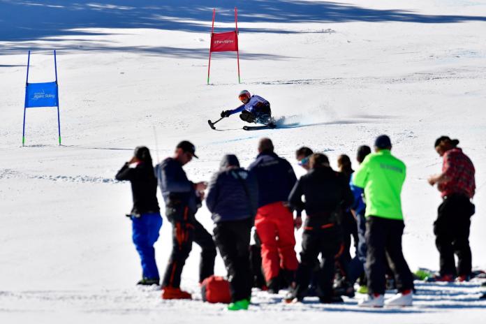 An athlete skis down the slope as about 10 officials watch.