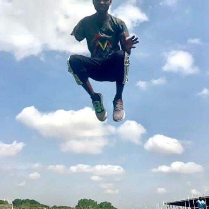 An upwards shot of a young man jumping high into the air.