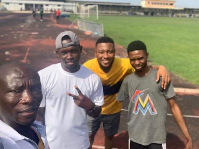 A selfie of a coach and three athletes on a track, including one young boy.