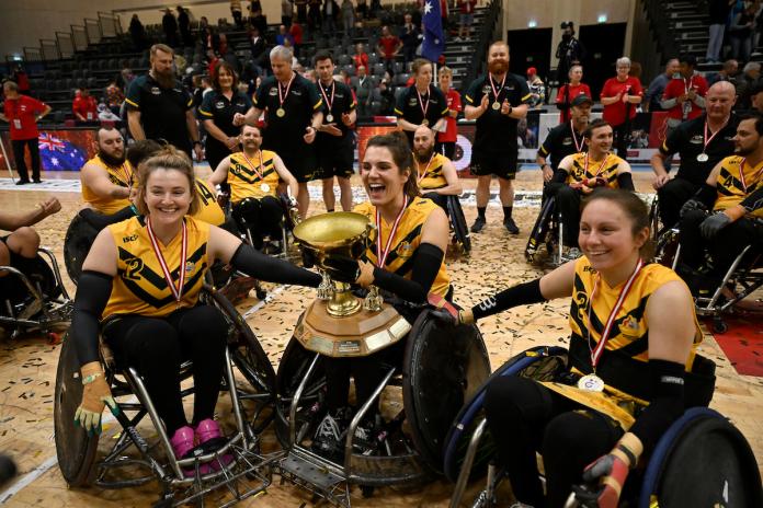 Three Australian female wheelchair rugby players lift the World Championship trophy