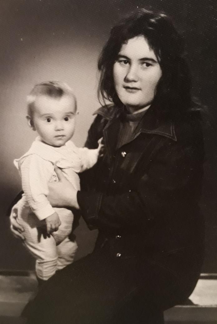 A 1970s black-and-white photo of a mother holding a baby girl in a photo studio.