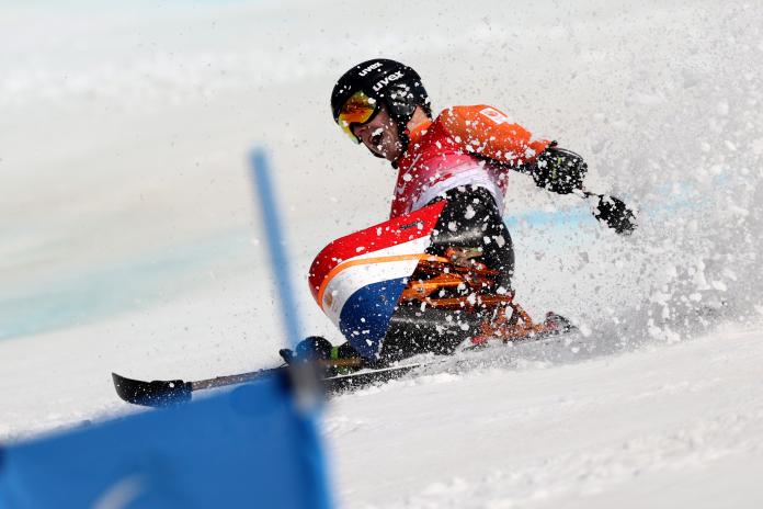A male sit skier yells as he loses balance, sending out a flurry of snow, on a giant slalom course at Beijing 2022.on a 