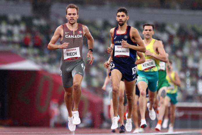 Male athletes run in a stadium at Tokyo 2020.