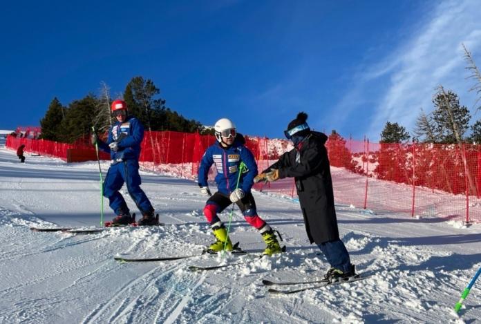 A coach speaks with an athlete on the slopes.