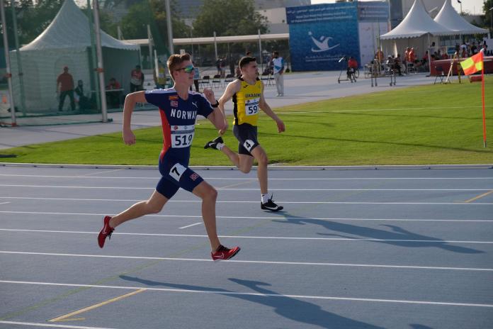 Two male runners, from Norway and Ukraine, race on the track during a competition.