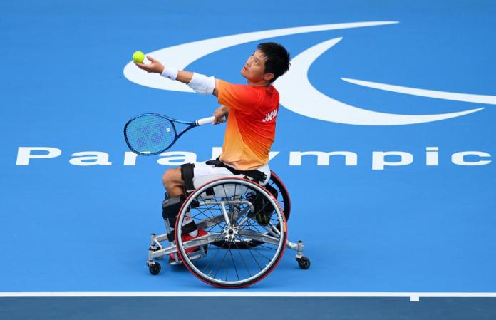 A male wheelchair tennis player prepares to serve the ball.