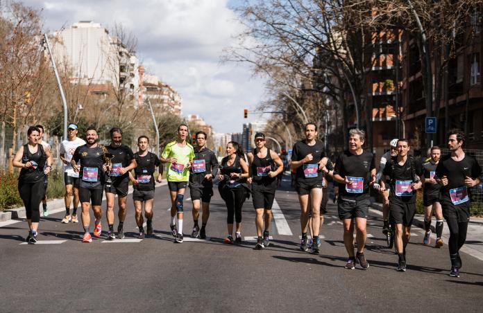 A man with cerebral palsy, wearing a neon green T-shirt, runs along the route with a group of runners in black.