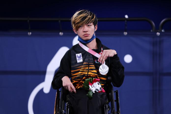 A male athlete holds a silver medal