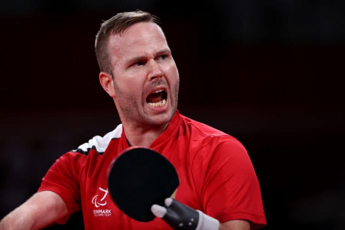 A male athlete holds a table tennis racquet.